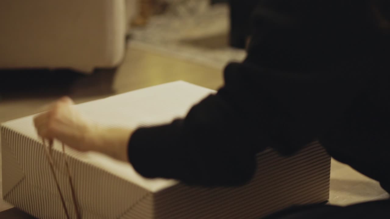 A Wrapped Christmas Gift is Gently Lifted by its Twine, Capturing a Simple, Cozy Holiday Moment - Close Up