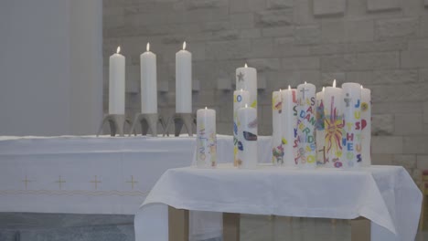 camera pans along several burning candles on an altar and a table