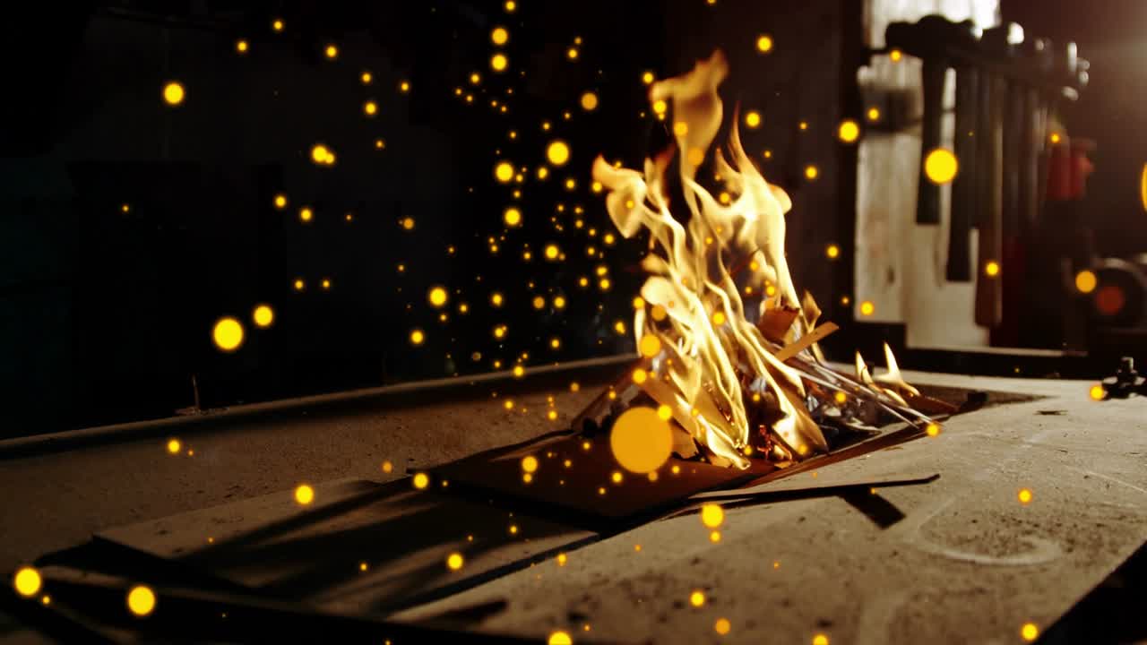 Funke entzündet glimmendes Papier, Flamme wächst, Glutpartikel treiben, zeigt Feuerausbreitung auf einer Werkbank.
