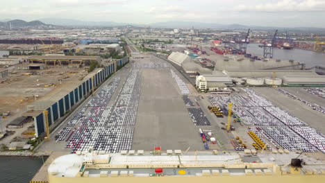 aerial view of logistics concept of commercial vehicles, cars and pickup trucks waiting to be load on to a roll-on-roll-off car carrier ship