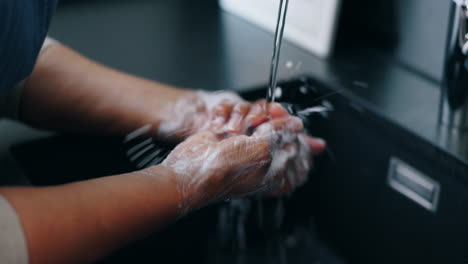 Agua,-Jabón-Y-Persona-Lavándose-Las-Manos-En-La-Cocina.