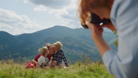 man photographing woman kids in front mountains. family enjoying photo session.