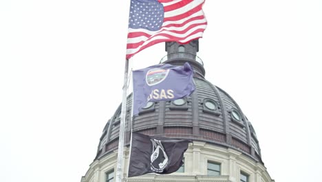 kansas state capitol building with flags waving in topeka, kansas with close up of flags stable video