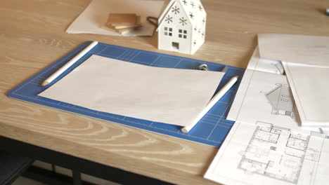 workspace of architect on wooden table with plans and blueprints