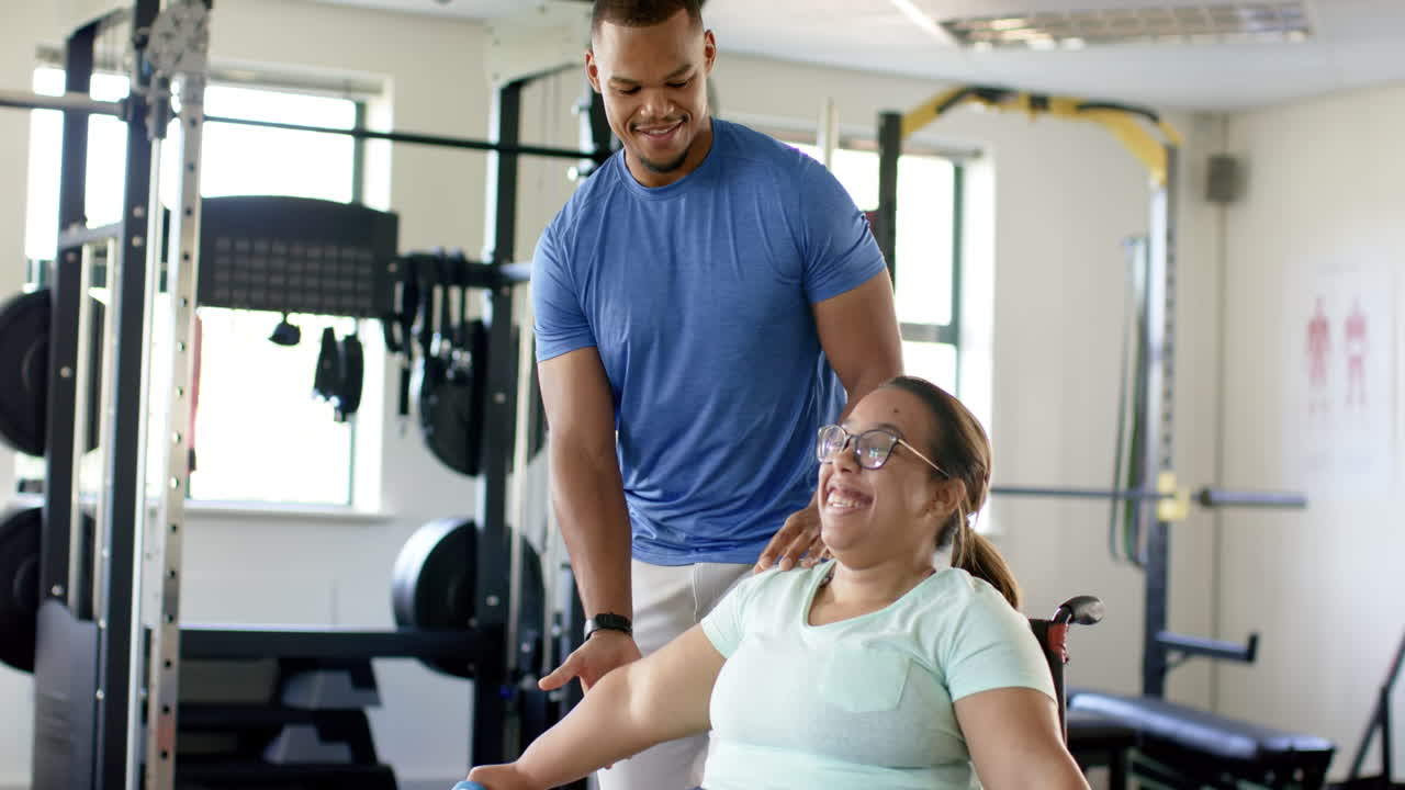 Assisting woman with paraplegia in wheelchair, personal trainer guiding rehabilitation exercises