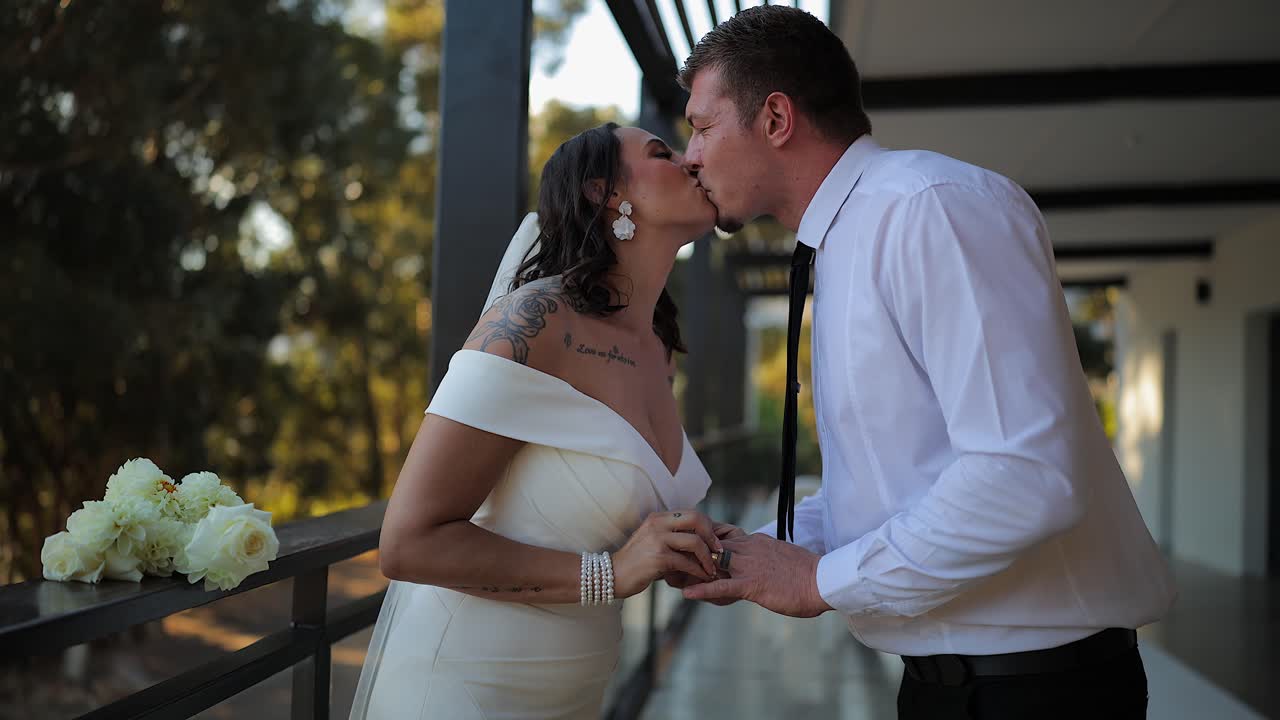 El día de la boda, la novia y el novio comparten un dulce beso en el patio del recinto.