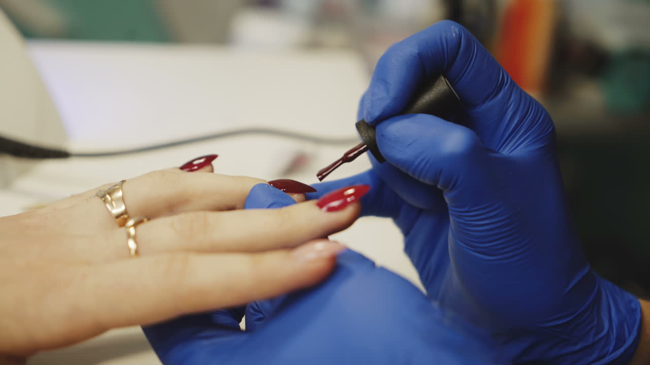 Master of manicure paints nails to the girl in the salon. Hand care in the spa.