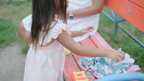 a pregnant mother and her young daughter enjoy playful time together at a playground in the park, surrounded by trees and greenery