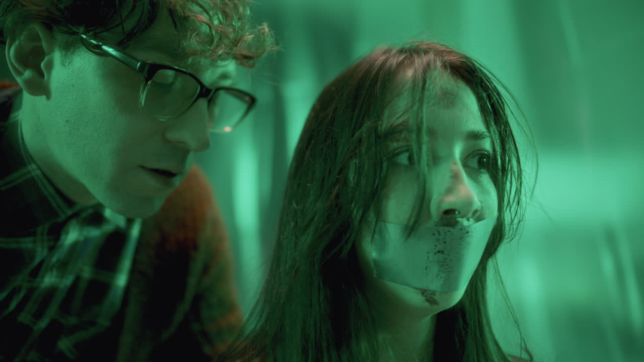 정신병자 살인범이 겁에 질린 인질의 귀에 위협을 속삭이고 입이 붙어 있습니다.