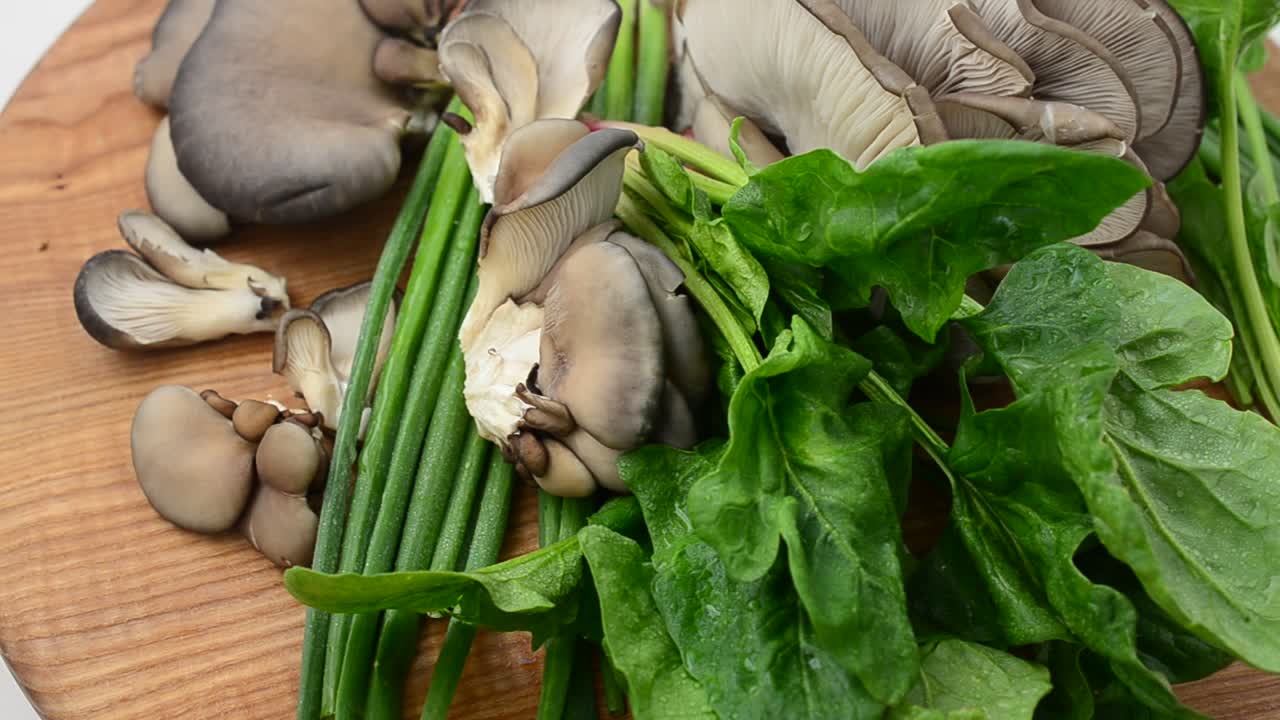 Spinach, onions and mushrooms of an oyster mushroom on a board. Oyster mushroom mushrooms on a board