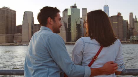 young couple talking by the river in manhattan, back view