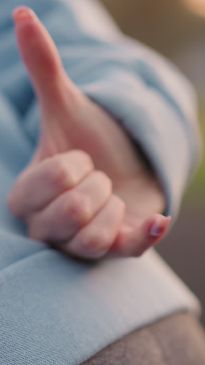 vista cercana de la cintura de la dama en suéter cian ligeramente doblada haciendo un gesto de la mano con un fondo borroso que muestra a otras damas involucradas en fitness o estirándose al aire libre