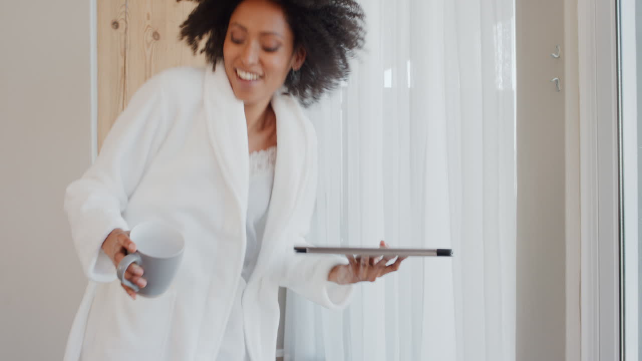 donna felice che balla a casa in pigiama che si diverte a festeggiare i successi dello stile di vita che si gode la danza felice nell'appartamento penthouse