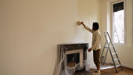 chimenea cubierta con plástico mientras se aplica pintura limewash en la pared de la casa junto a la ventana