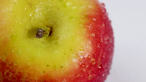 Macro video of a rotating apple with water droplets, highlighting texture and vibrant colors under bright lighting