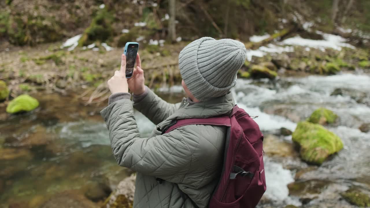 Woman taking picture of a stream in a forest