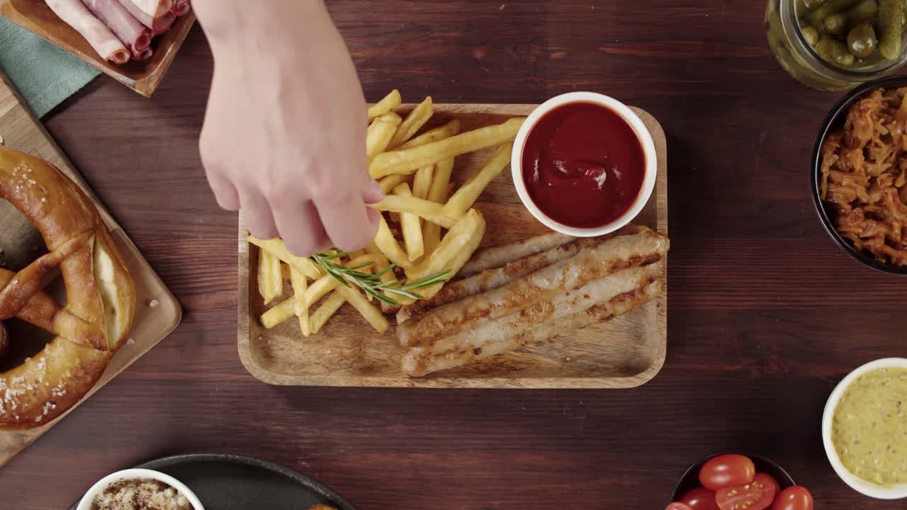 Persona che intinge una patatina fritta nel ketchup su un tavolo con cibo tedesco