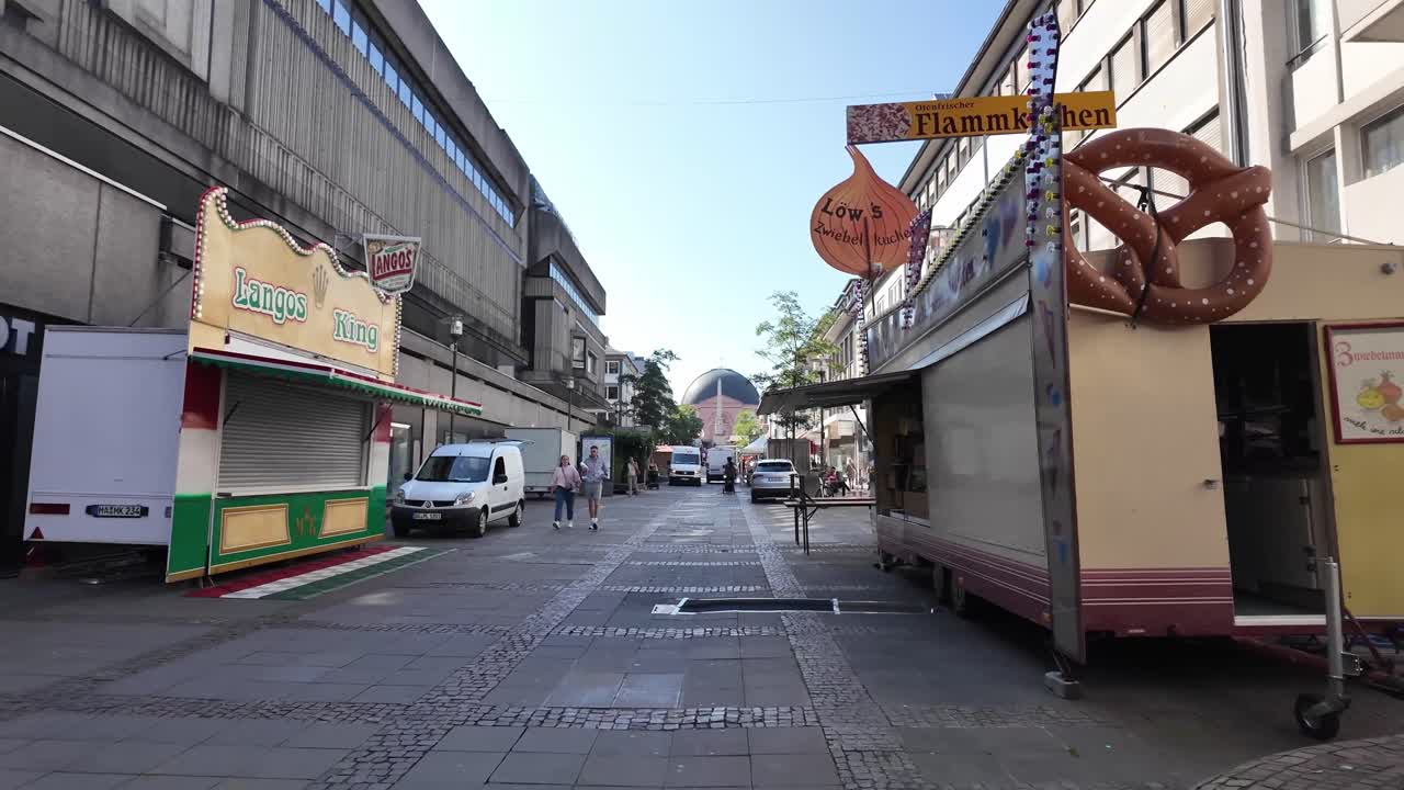 Early morning in Darmstadt in shopping district with food trucks and passerby people. Hessen. Germany