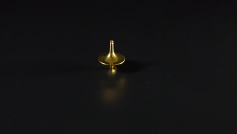 golden spinning top on a black surface