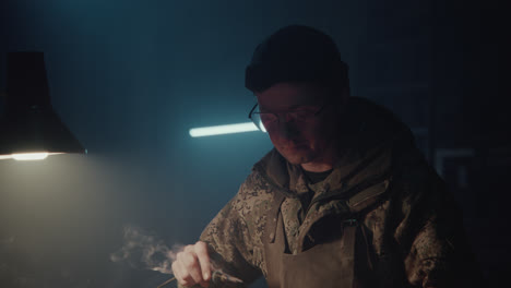 a bombmaker assembles a bomb in his workshop at night