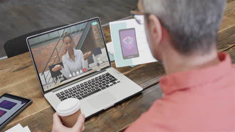 Caucasian-businessman-on-laptop-video-call-with-african-american-female-colleague-on-screen