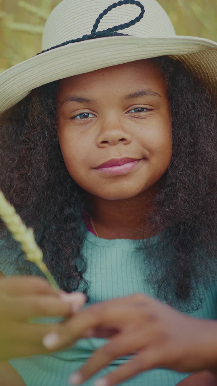 Girl in a hat holding wheat in a field