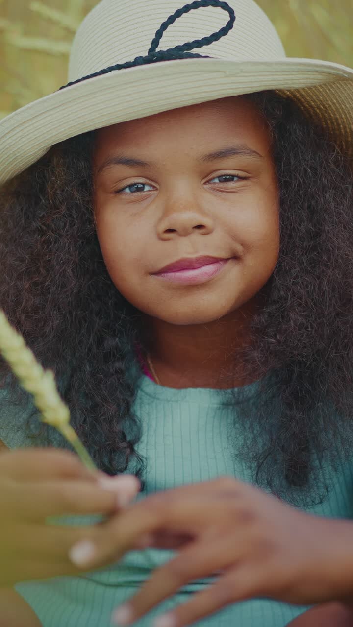 Girl in a hat holding wheat in a field
