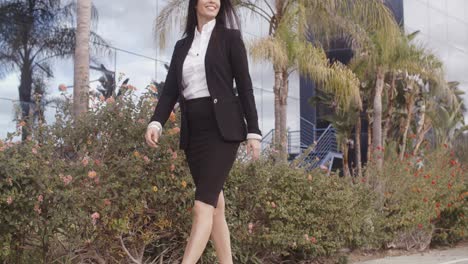 mujer confiada sonriente que camina a lo largo de una acera