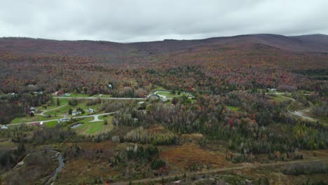 Aerial-view-of-residential-area-near-colorful-fall-forest-on-hillside