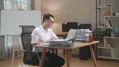 사무실 에서 문서 를 처리 하는 동안 노트북 으로 비디오 통화를 하는 아시아인