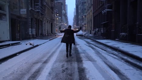 man walks away moodily away from the camera making victory sign on snowy street in soho, manhattan