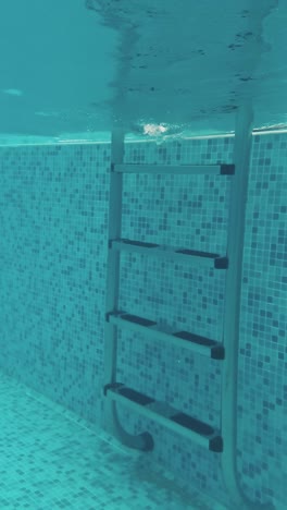 un joven nada bajo el agua en una piscina.