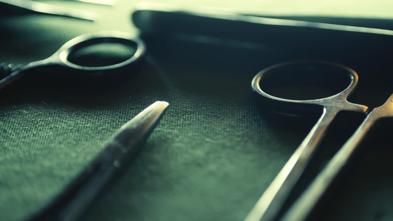 Surgical medical instruments laid out on green linen CLOSE-UP slide reveal