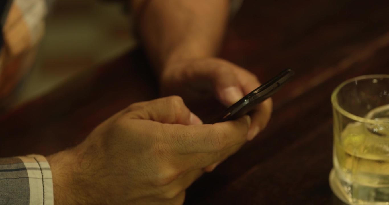 Mani che prendono il cellulare e digitano. Scena in un bar. Carrellata