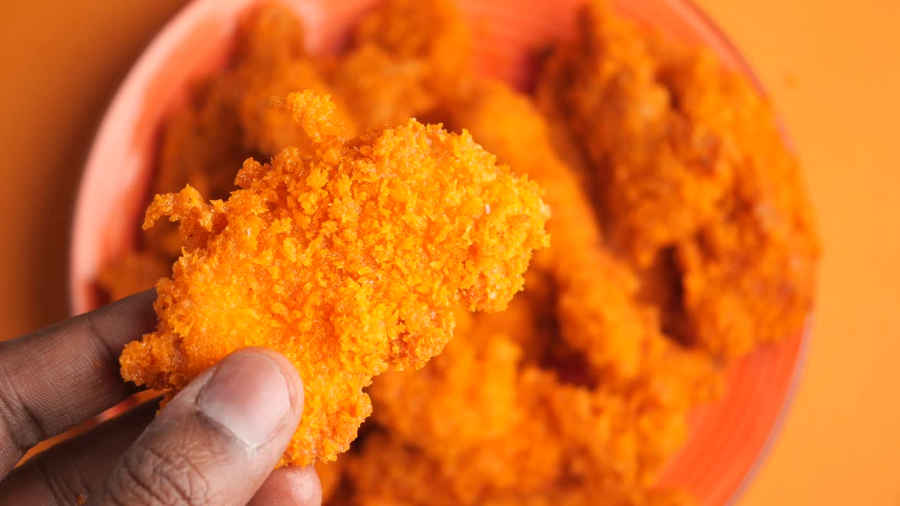 Hand holding a crispy fried chicken tender