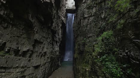 vuelo oscuro de humor entre estrechos acantilados de roca hacia una gran cascada