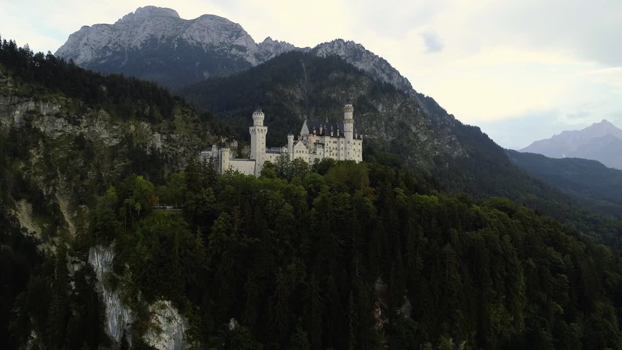 Aerial uprising shot of the famous castle Neuschwanstein orbiting around in bavaria germany revealing the stunning alps mountains landscape