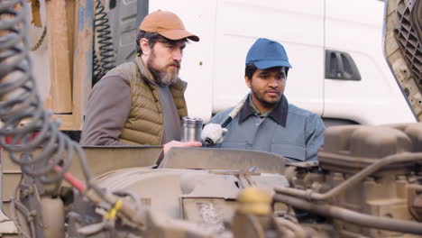 jefe y trabajador revisando el motor del camión en un parque logístico