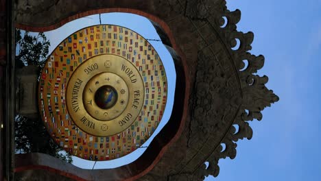 Vertical-Wide-angle-shot-of-the-World-Peace-Gong-in-Bali-during-the-golden-or-blue-hour-at-sunset-with-palm-trees,-trees-and-the-moon-in-the-background