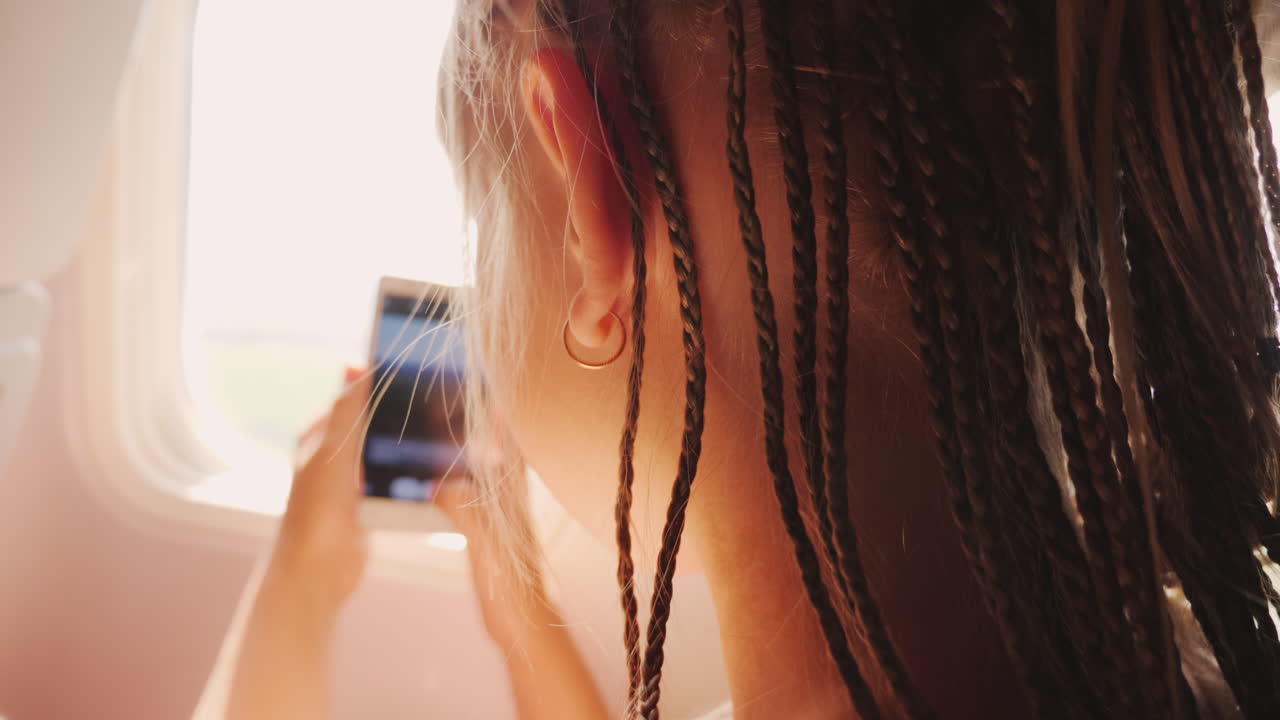 el niño regresa de vacaciones - hace fotos con un teléfono inteligente a través de la ventana del avión afr