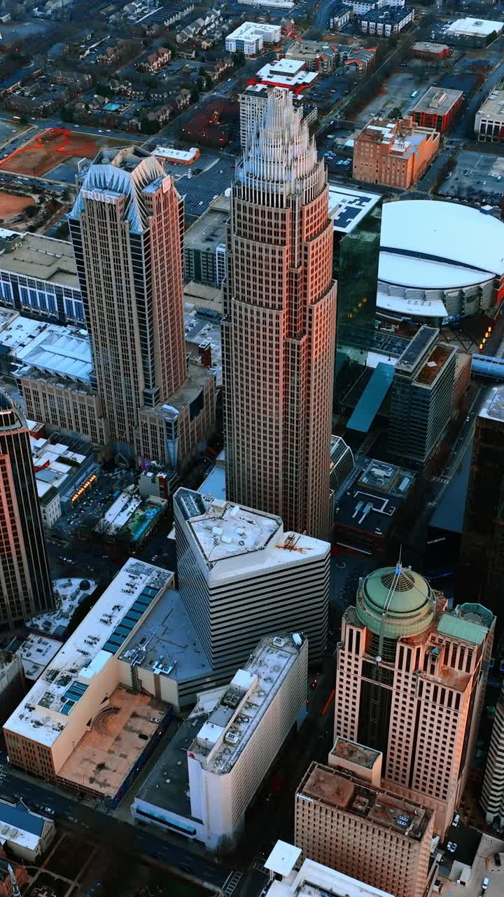 Allontanandosi dall'edificio più alto di Charlotte, NC, USA. Vista aerea del panorama cittadino al crepuscolo. Video verticale.