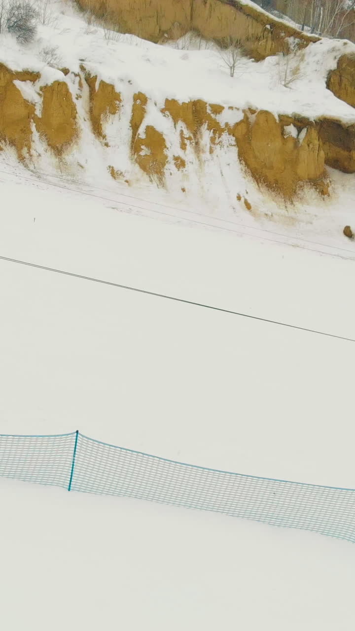aerial motion along modern automated t-bar lift at ski resort snowy track on mountain slope on nasty day