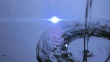 Animation-of-water-drops-dropping-into-blue-water-with-glowing-light