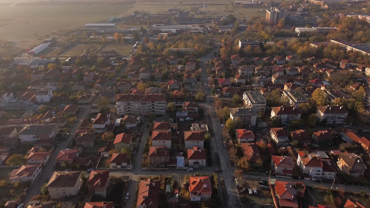 Golden hour drone footage flying over the rooftops of Sopot, Bulgaria, with warm sunlight casting long shadows and highlighting the town's charming architecture