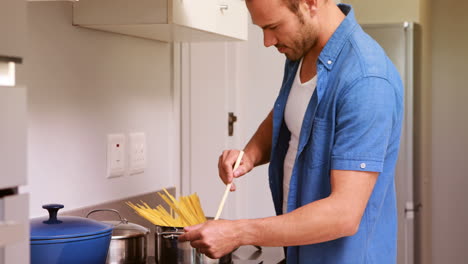 hombre sonriente poniendo pasta en una sartén