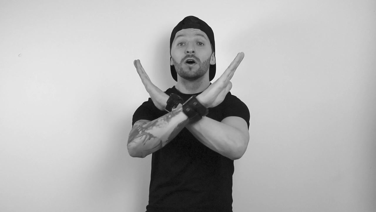 Grayscale footage of a tattooed man disagreeing with something while being very angry and intense. Man is waving hands around the neck and making a cross by crossing arms and stop it motion with hands