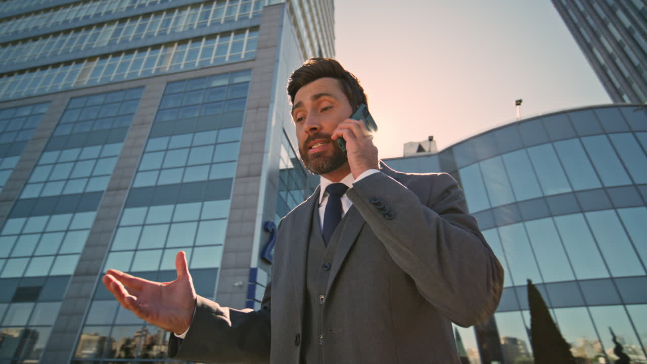 hombre de negocios furioso gritando altavoz de teléfono inteligente en la luz del sol de la calle de cerca