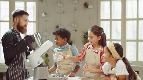 chef mostrando crema batida a los niños en la clase magistral de cocina