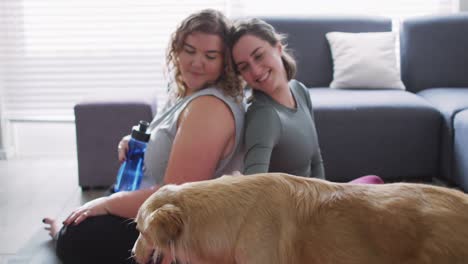 pareja de lesbianas caucásicas manteniéndose en forma y descansando con el perro