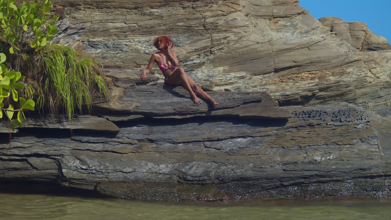 Il suono delicato delle onde ritmiche fa da colonna sonora a una ragazza in bikini dai colori vivaci che si gode una mattinata tranquilla su una spiaggia tropicale incontaminata